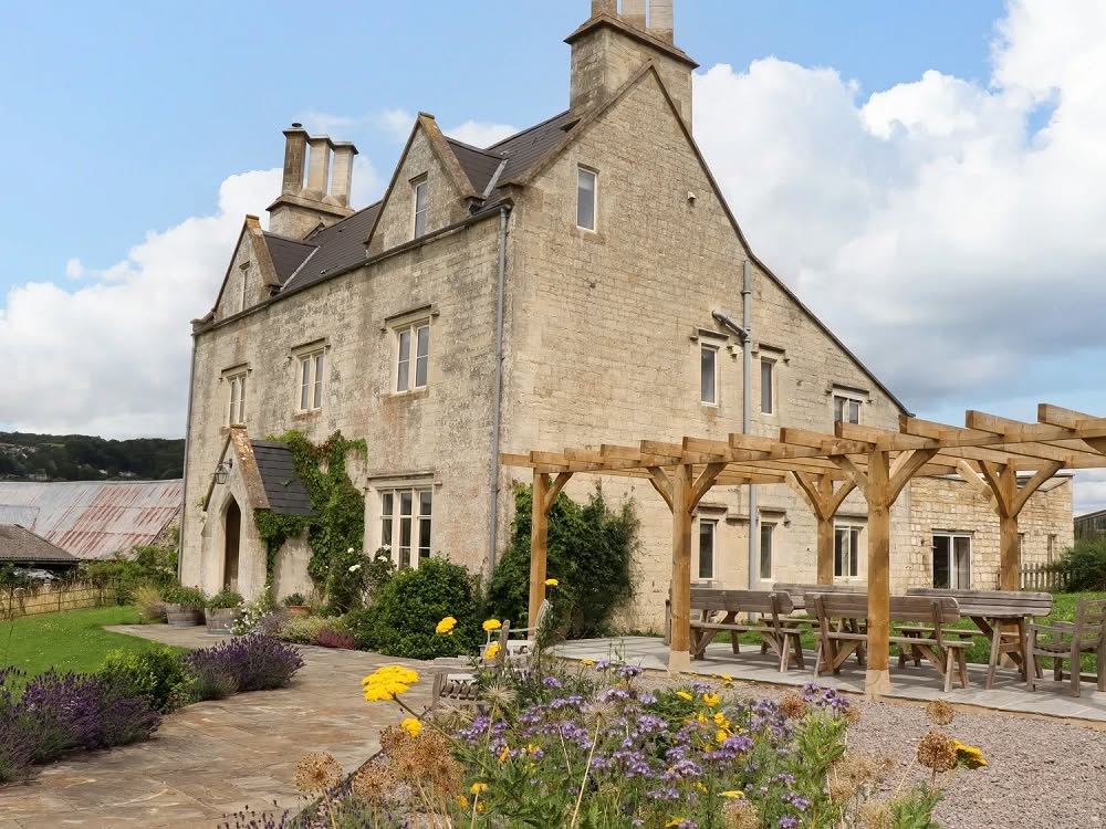 The Cotswolds Juice Retreat house and garden, with seating and village backdrop, Cotswolds UK